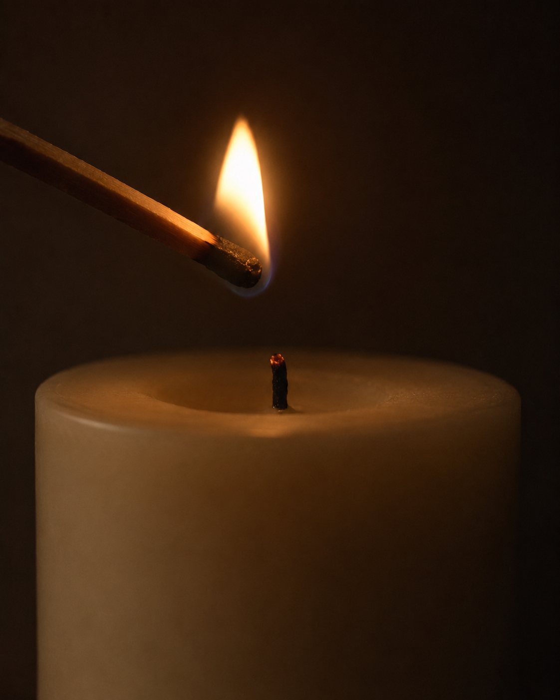 Warum ich dir keinen Erfolg verspreche 2 Ein brennendes Streichholz berührt den Docht einer noch dunklen Kerze, ein kleiner warmer Lichtpunkt im Dunkeln